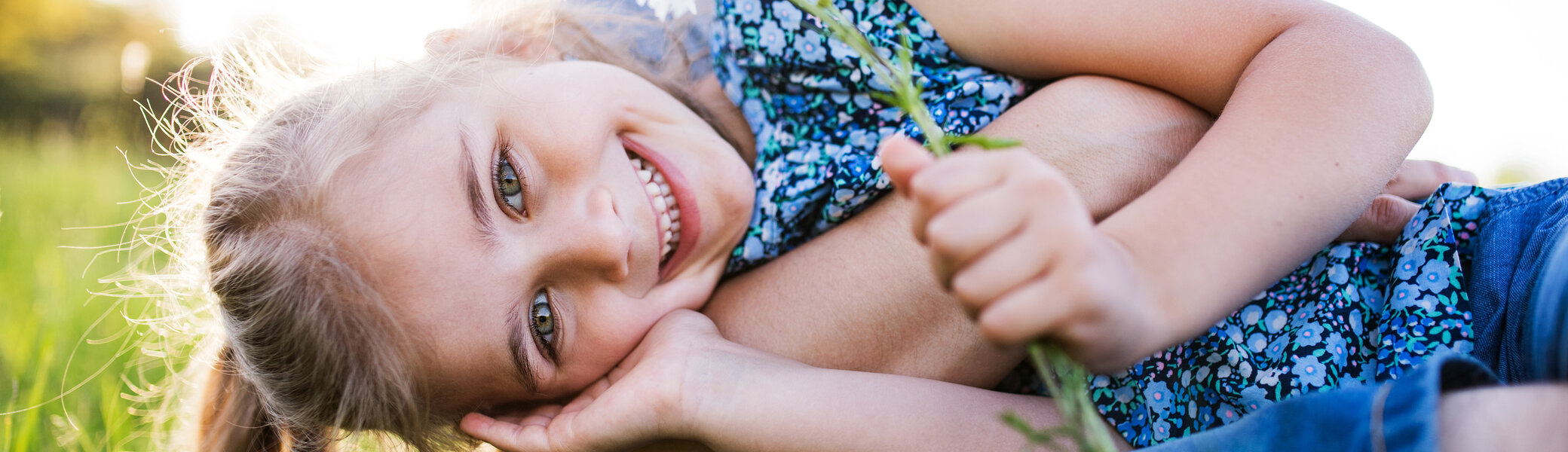 Ein Mädchen mit ihrem Vater auf einer Frühlingswiese | © Halfpoint / Adobe Stock